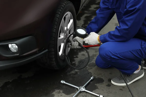 Worker checking tire pressure in car wheel at service station, c — 스톡 사진