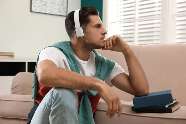 Muž poslouchající audioknihu u pohovky doma — Stock fotografie