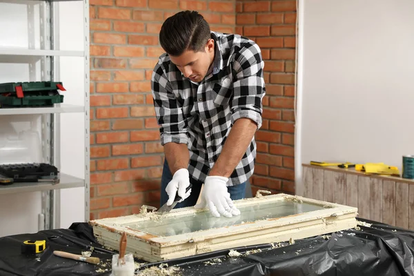 Man repareert oude beschadigde raam aan tafel binnen — Stockfoto