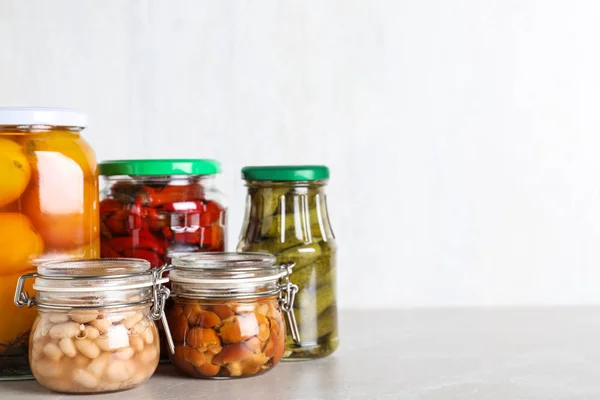 Üvegedények különböző pácolt zöldségekkel, világos márvány fülön — Stock Fotó