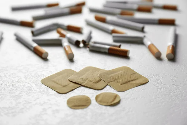 Nicotine patches and cigarettes on white table, closeup