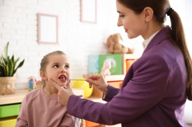 Konuşma terapisti, küçük Gi ile seansta logopedik sonda kullanıyor.