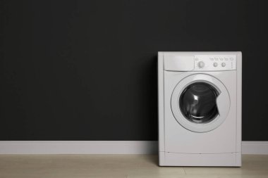 Siyah duvarın yanında modern çamaşır makinesi, yazı için yer var. Çamaşır. 