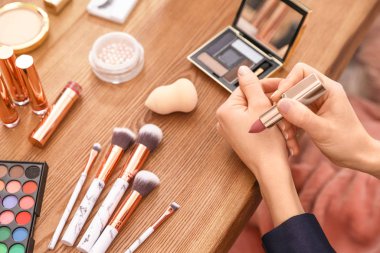 Güzellik blogcusu masada ruj örneği alıyor, yakın plan.