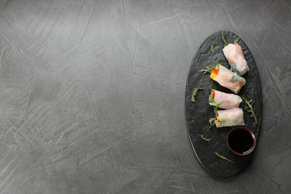 Delicious rolls wrapped in rice paper served on grey table, top view. Space for text