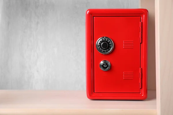 Red steel safe with mechanical combination lock on shelf. Space for text