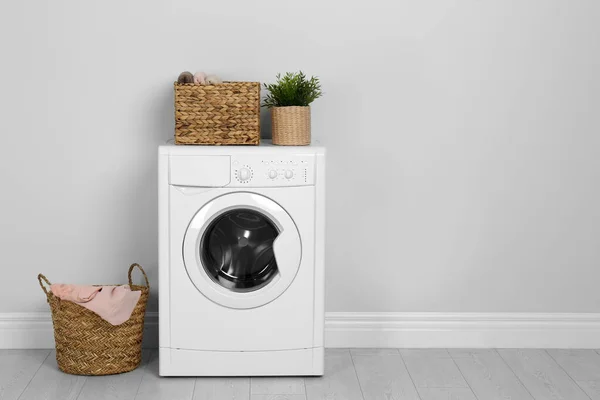 Modern washing machine with houseplant and laundry baskets near — 스톡 사진