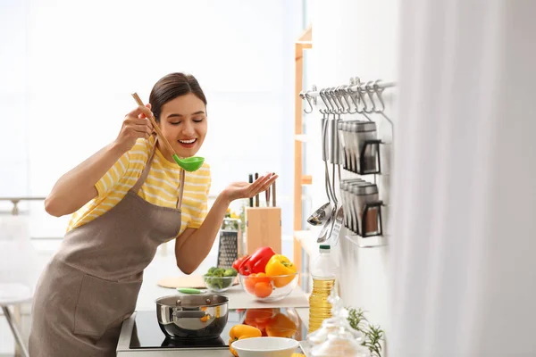 Mujer joven cocinando sabrosa sopa en la cocina — Foto de Stock