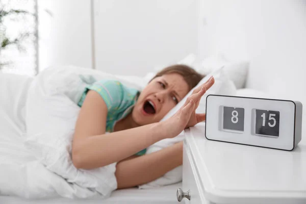 Clock and sleepy young woman at home in morning, focus on hand — Stock Photo, Image