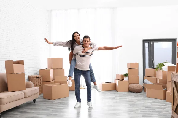 Happy couple having fun in room with cardboard boxes on moving d — 스톡 사진