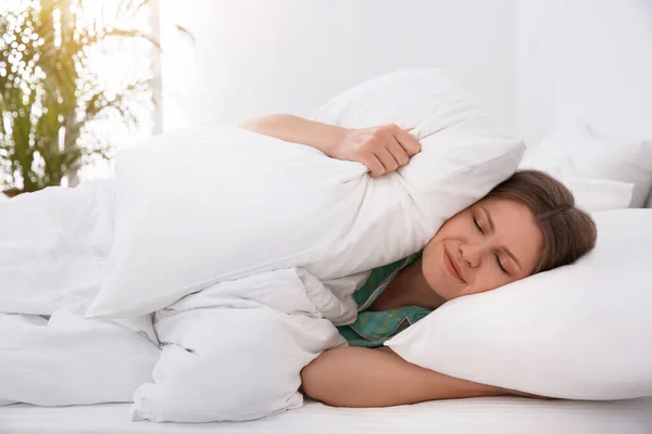 Jeune femme endormie couvrant les oreilles avec des oreillers à la maison le matin — Photo