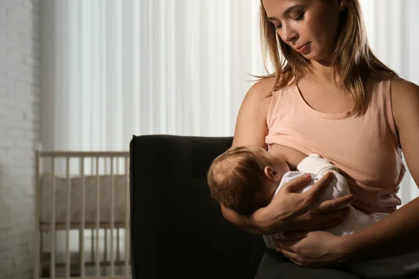 年轻妇女在家里用母乳喂她的小宝宝 案文的篇幅 — 图库照片