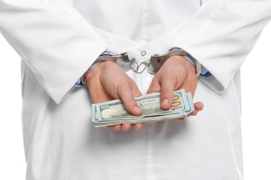 Beyaz arka planda rüşvetle kelepçelenmiş bir doktor, yakın plan. Cor