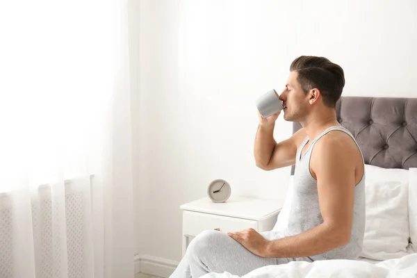 Man with cup of coffee in bedroom. Lazy morning — 스톡 사진