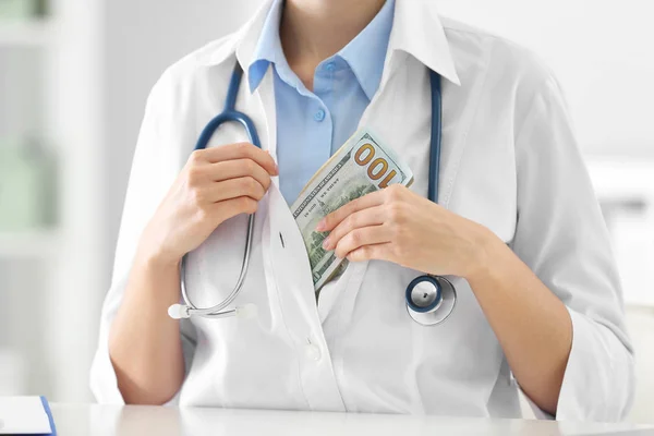 Doctor putting bribe into pocket at desk in clinic, closeup. Cor — Stock Photo, Image