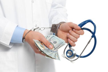 Doktor, rüşvetle kelepçelenmiş ve steteskop takmış.