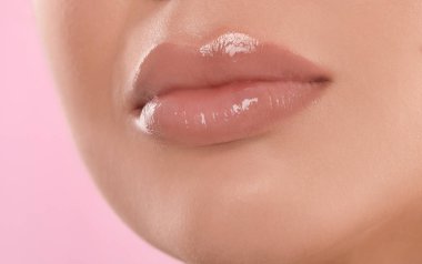 Pembe arka planda güzel dolgun dudakları olan genç bir kadın, yakın plan.