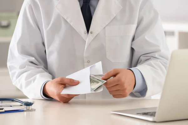 Doutor com suborno na mesa na clínica, close up. Medicamento corrompido — Fotografia de Stock