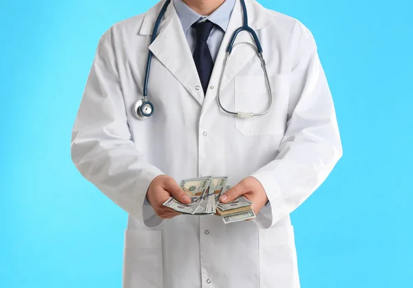 Lekarz z łapówką na jasnoniebieskim tle, zbliżenie. Korupcja — Zdjęcie stockowe