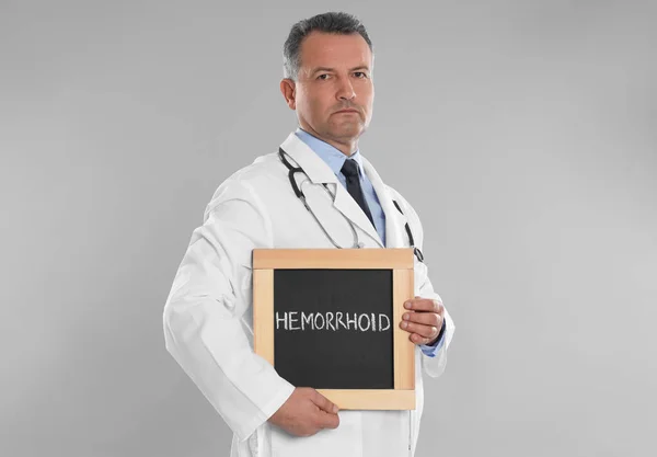Doctor Holding Blackboard Word Hemorrhoid Light Grey Background — 스톡 사진