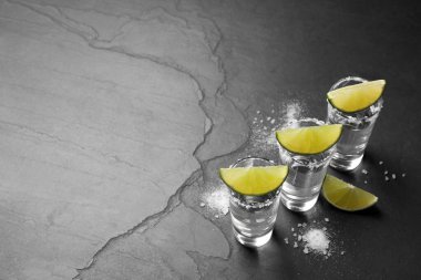 Meksika tekilası, limon dilimleri ve siyah masaya tuz. Metin için boşluk