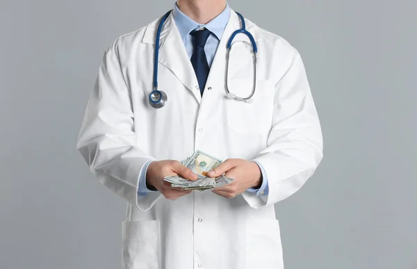 Doctor with bribe on grey background, closeup. Corruption in med — Stock Photo, Image