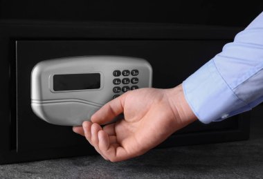 Siyah çelik kasayı elektronik kilitle açan adam, yakın plan.