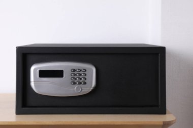 Ahşap masada elektronik kilidi olan siyah çelik kasa.