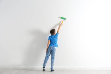 Beyaz duvarda paten fırçasıyla küçük çocuk resimleri.