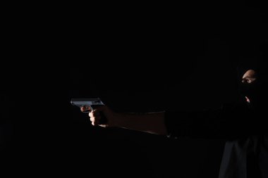Professional killer with gun on black background