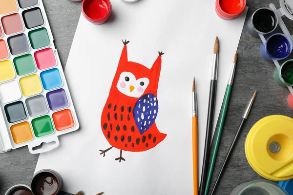Flat lay composition with child\'s painting of owl on grey table