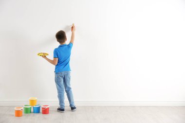 Beyaz duvarlara resim yapan küçük bir çocuk. Metin için boşluk