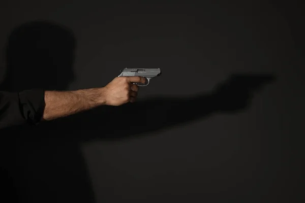 Tueur professionnel avec pistolet sur fond noir, gros plan — Photo