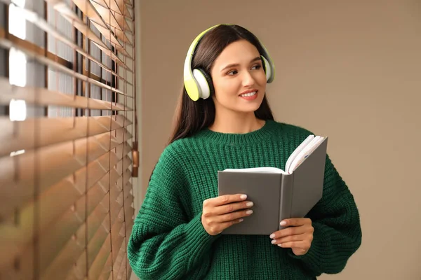 Νεαρή Γυναίκα Που Ακούει Ακουστικό Βιβλίο Κοντά Στο Παράθυρο Εσωτερικούς — Φωτογραφία Αρχείου
