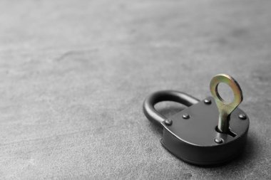 Gri arka planda anahtarı olan çelik asma kilit, metin için boşluk. Güvenlik kavramı