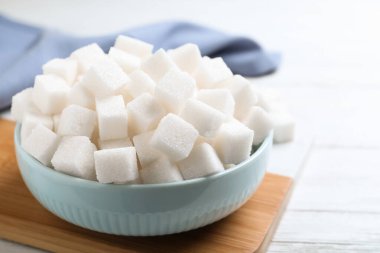 Refined sugar cubes on white wooden table
