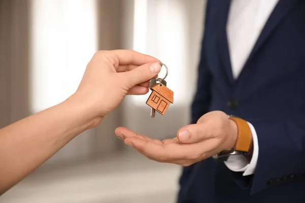 Immobilienmakler übergibt Schlüssel mit Schmuckstück an Klient im Büro, c — Stockfoto