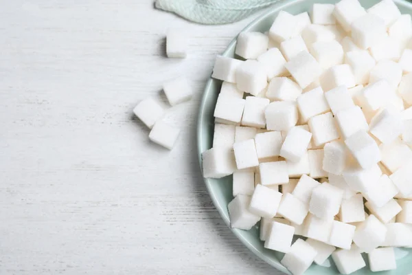 Cubos de azúcar refinados en mesa de madera blanca, puesta plana —  Fotos de Stock
