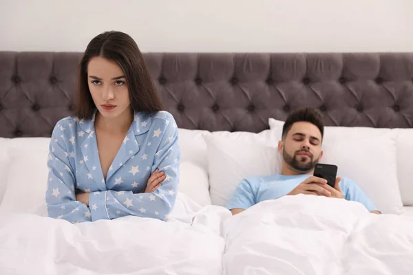 Joven hombre prefiriendo teléfono inteligente sobre su novia en la cama en ho — Foto de Stock