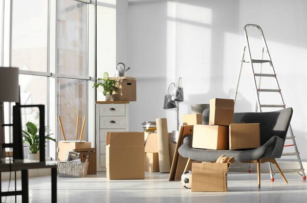 Картонные коробки и домашние вещи в гостиной. День переезда
