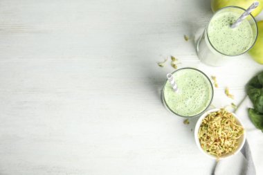 Flat lay composition with green buckwheat smoothie on white wooden table, space for text
