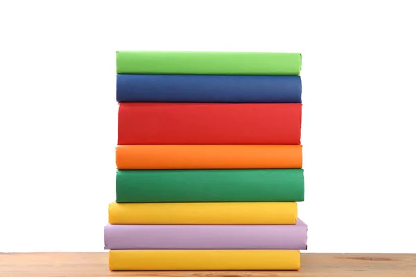 Pilha de livros coloridos em mesa de madeira contra fundo branco — Fotografia de Stock