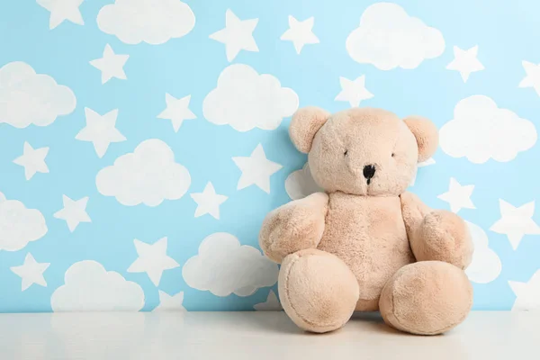 Teddy bear on white table near wall with painted blue sky, space — Stock Photo, Image