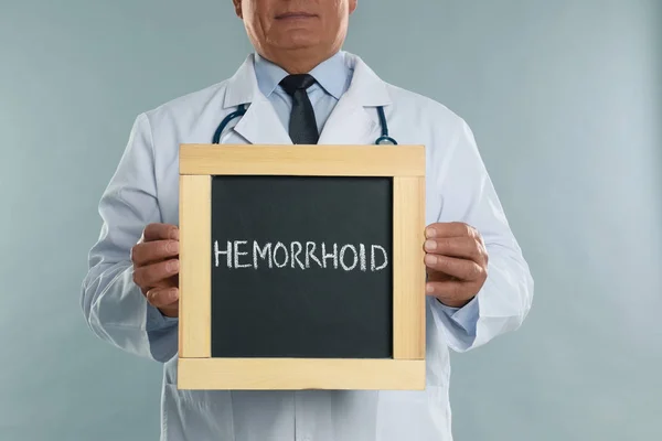 Doctor Sosteniendo Pizarra Con Palabra Hemorrhoid Sobre Fondo Gris Claro — Foto de Stock