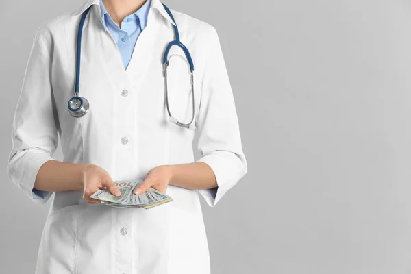 Dokter met omkoping op grijze achtergrond, close-up. Corruptie in de gezondheidszorg — Stockfoto