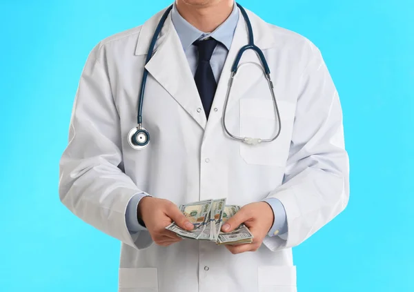 Doctor with bribe on light blue background, closeup. Corruption — 스톡 사진
