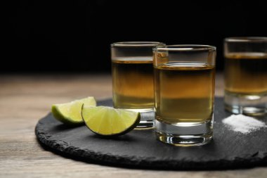 Meksika tekilası, limon dilimleri ve ahşap masada tuz.