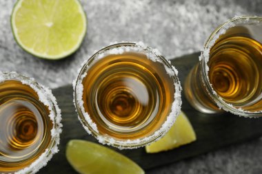 Meksika tekila shot 'ı, limon dilimleri ve gri masada tuz, üst manzara.