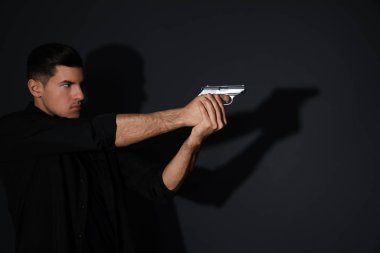 Professional killer with gun on black background