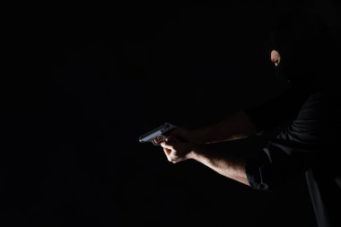 Professional killer with gun on black background